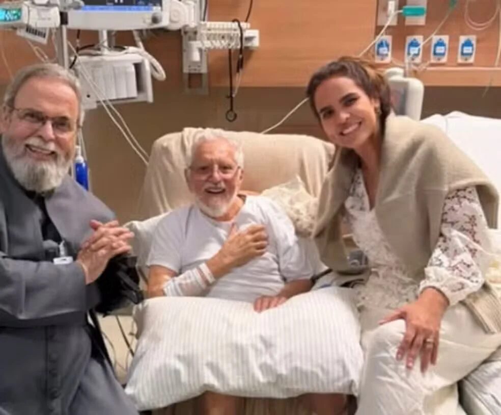 Carlos Alberto de Nóbrega reaparece sorridente após cirurgia no coração e recebe visita de padre